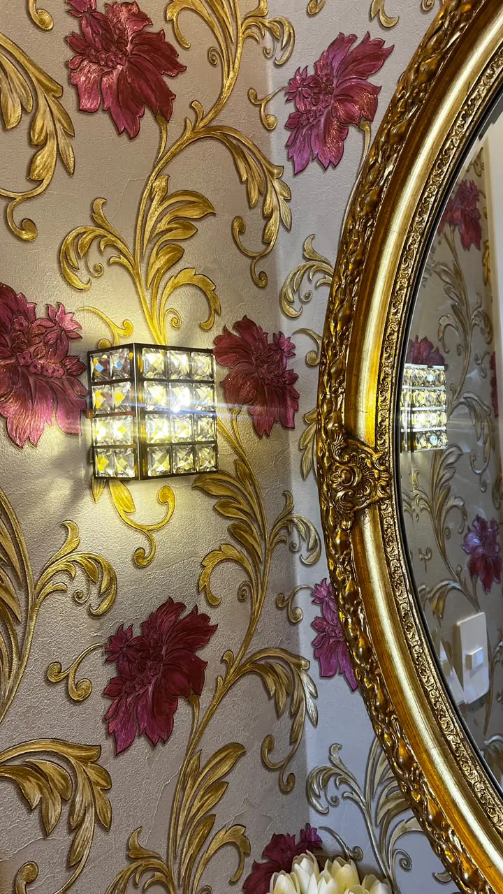 Espelho dourado, arandela e decoração floral em bordô e dourado
